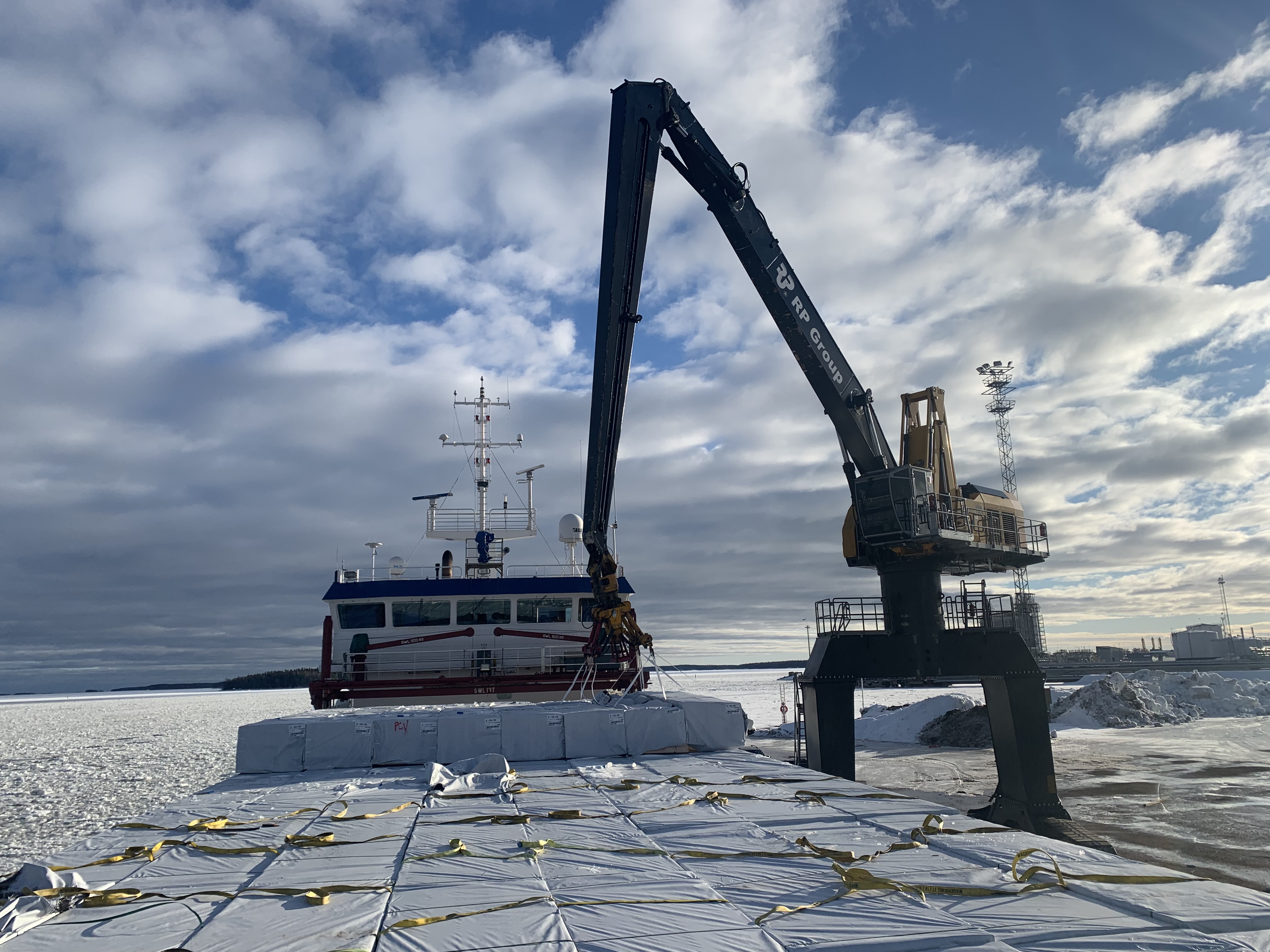 The crane is slowly loading all the timber on deck with the slings
