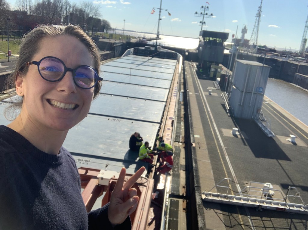 Chief officer Sophie taking a selfie from the bridge after a manoeuvre , overlooking the crew chatting on the hatches in the locks